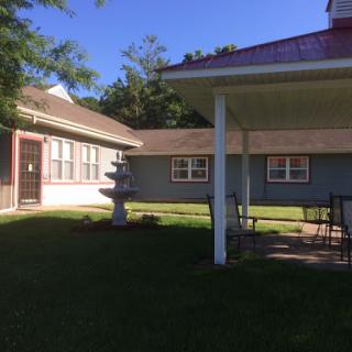 A peaceful outdoor area featuring a fountain and seating, surrounded by well-maintained grass.