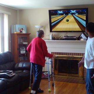 Two people playing a bowling video game in the living room.