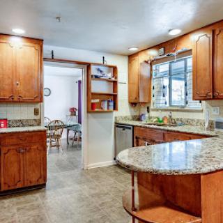 A well-designed modern kitchen featuring wooden cabinets and a granite countertop, seamlessly connected to a cozy dining area.