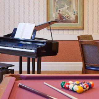 A cozy room featuring a piano with sheet music and a pool table with arranged billiard balls.
