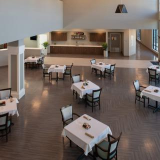 An empty restaurant dining area with neatly arranged tables and chairs, featuring a modern and spacious interior.
