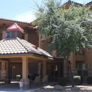 A residential building with a tiled roof and a tree in the front yard.
