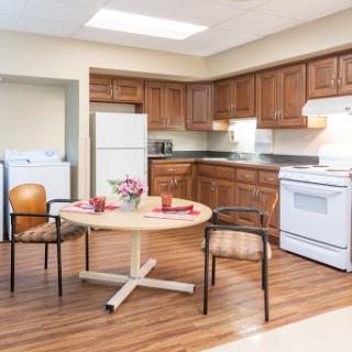 A cozy and well-lit kitchen featuring a round dining table with chairs, modern appliances, and wooden flooring.