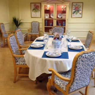 A well-set dining table in a formal dining room, complete with floral patterned chairs and elegant dinnerware.
