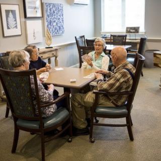 A group of senior individuals socializing at a table in an indoor setting.