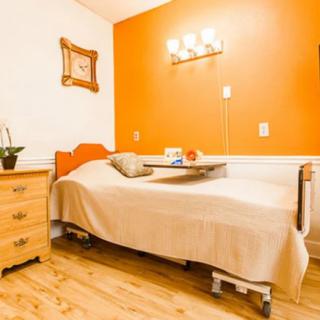 A cozy bedroom with an orange accent wall, featuring a single bed and warm lighting.