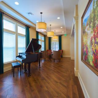 A spacious living room with a grand piano and elegant furnishings.