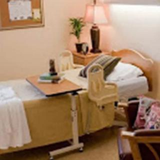 A tidy hospital room with a bed, chair, and medical equipment.