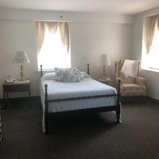 A cozy bedroom with a bed, two bedside tables with lamps, and soft natural light filtering through the windows.