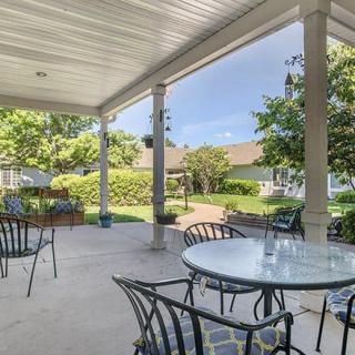 A spacious patio with tables and chairs overlooking a well-maintained garden.