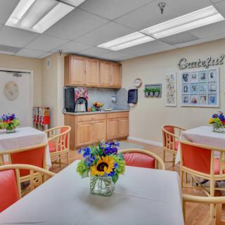 A cozy kitchen and dining area with neatly arranged tables and vibrant flower centerpieces.