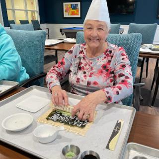A joyful moment as a senior resident prepares sushi with care and enthusiasm.