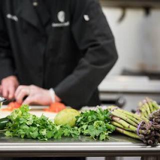 A chef preparing a meal with fresh vegetables in the kitchen.