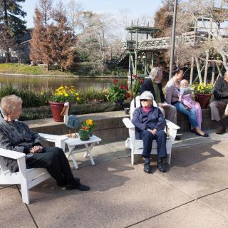 A group of people sitting and socializing in a park on a sunny day.
