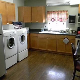 A multifunctional kitchen and laundry space featuring wooden cabinets and appliances.