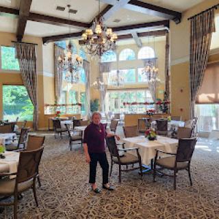 A spacious and elegantly designed dining area featuring large windows, stylish chandeliers, and comfortable seating.