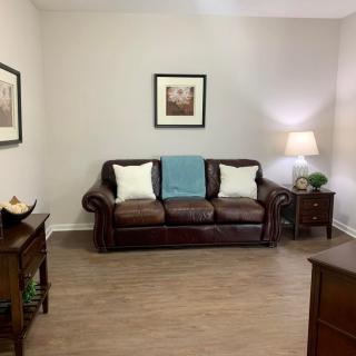 A cozy living room with a leather sofa, side tables, and framed artwork on the walls.