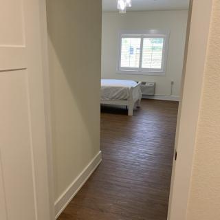 A minimalist bedroom with a wooden floor and a window providing natural light.