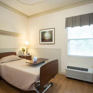 A neatly arranged hospital room with a single bed and a window.