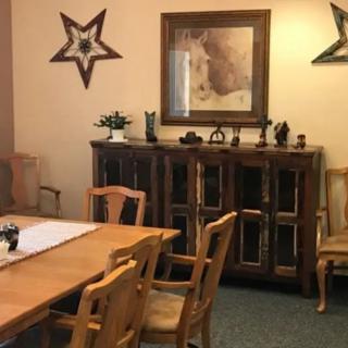 A cozy dining room with a wooden table and chairs, featuring decorative wall art and a cabinet.