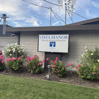 Vista Manor sign surrounded by blooming flowers.