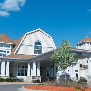 Suburban residential building with a tree under a clear blue sky.