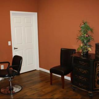 A well-decorated room with a chair, desk, and potted plant beside a white door.
