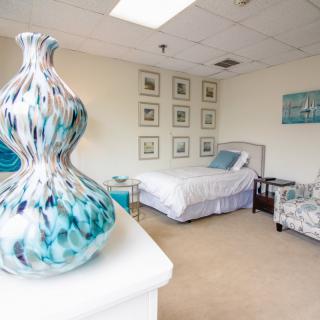 A modern bedroom featuring a bed, decorative vase, and framed artwork on the walls.