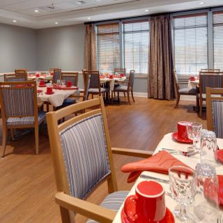 A well-arranged dining room with tables set for a meal, featuring elegant place settings and comfortable seating.