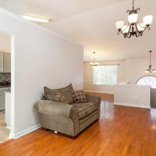 A cozy living room with a single sofa, hardwood flooring, and a chandelier.