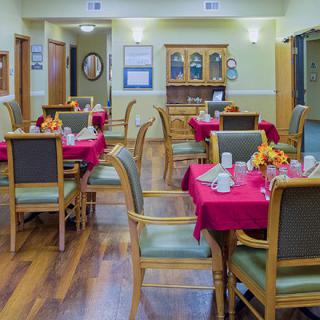 A cozy dining room with tables set up for guests, featuring red tablecloths and elegant decor.