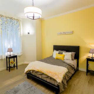 A cozy bedroom with a yellow accent wall and modern decor.
