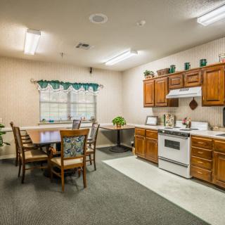 A cozy kitchen and dining area with wooden cabinets, a stove, and a table with chairs.