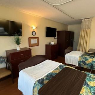 A shared hospital room with two beds, TVs, and a curtain divider.