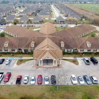 Aerial view of a large building with a surrounding parking lot in a suburban area.
