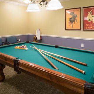 A cozy game room featuring a pool table with cue sticks neatly arranged on its surface.