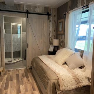 A cozy modern bedroom featuring a sliding barn door and wood flooring.