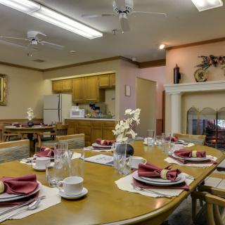 A well-decorated dining room with a table set for a meal, adjacent to an open kitchen.