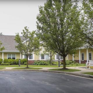 A suburban residential building surrounded by trees and a paved road.