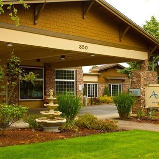 A well-maintained building entrance with a decorative fountain and lush landscaping.