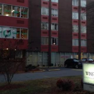 A building with multiple windows and a sign in front, taken during evening hours.
