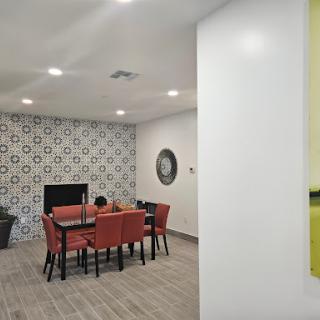 A stylish dining area featuring a modern table and orange chairs against a decorative tiled wall.