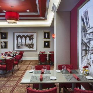 A modern restaurant interior featuring red decor with elegant wall art and neatly arranged tables and chairs.