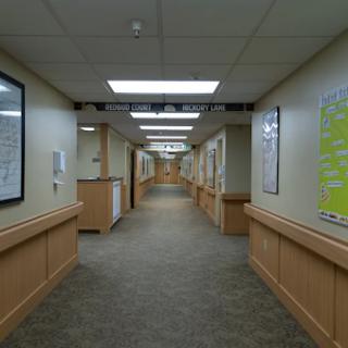 A well-lit hallway featuring wooden paneling and various posters on the walls.