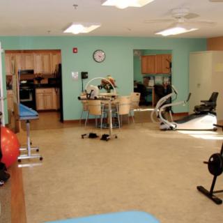 A rehabilitation room equipped with various exercise machines and furniture for therapy sessions.