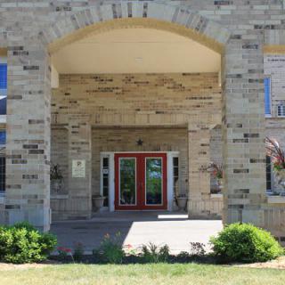 A stone building entrance with an archway and red doors.