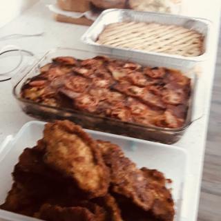 A table with an assortment of homemade baked dishes and fried food.