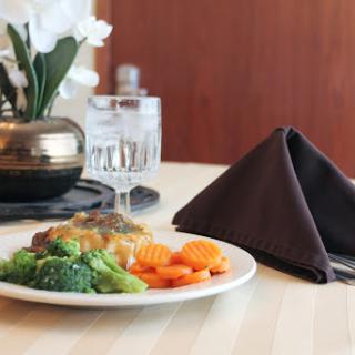 A beautifully arranged plate of vegetables and protein, elegantly served with a glass of water.