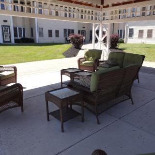 Outdoor seating area with wicker chairs and tables in a courtyard setting.