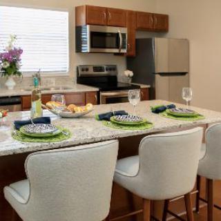 A modern kitchen with a dining area, featuring a kitchen island set for a meal, and equipped with stainless steel appliances.